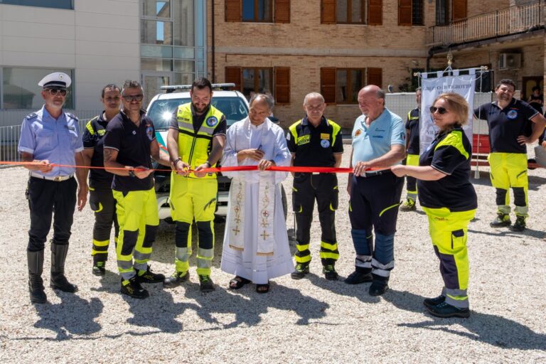 Il taglio del nastro davanti al nuovo pickup, con volontari, un agente della Polizia Locale e il parroco