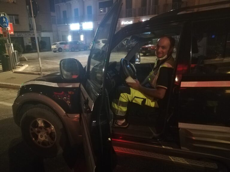 Un volontario al posto di guida del fuoristrada, di notte, in una via del centro