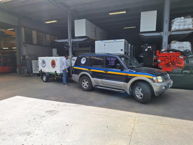 Il fuoristrada agganciato al carrello Emergency dentro il magazzino del fornitore, con un volontario accanto