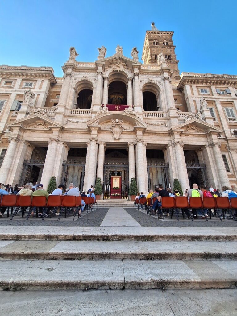 La facciata della basilica di Santa Maria Maggiore con le sedie disposte davanti all'ingresso e la gente in attesa