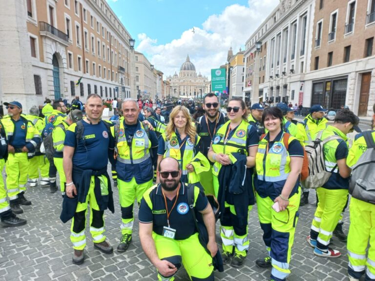 Sei volontari del Gruppo CB Tigrotto in divisa gialla in via della Conciliazione, con la cupola di San Pietro sullo sfondo
