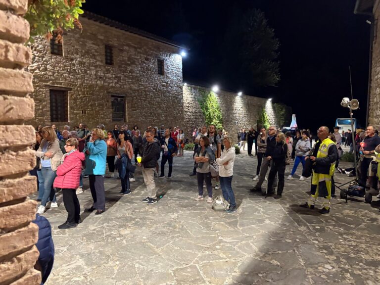 Il piazzale lastricato del convento di Renacavata di notte, illuminato dai fari: decine di pellegrini in piedi ad ascoltare, e sulla destra un volontario del Gruppo CB Tigrotto in divisa ad alta visibilità accanto agli altoparlanti montati su un'asta